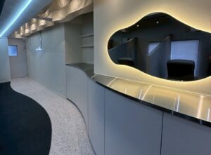 「ME.REBO原宿D/O店の受付カウンター。有機的なフォルムのミラーと間接照明が上質な雰囲気を演出」