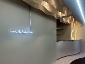 「ME.REBO原宿D/O店の受付カウンター。有機的なフォルムのミラーと間接照明が上質な雰囲気を演出」