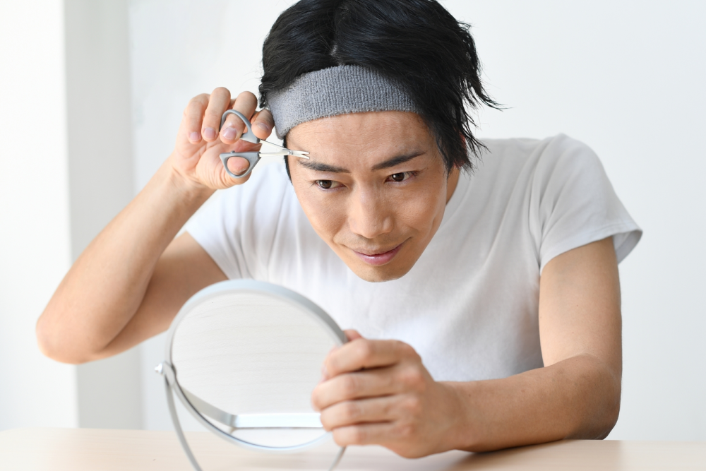 自分で眉毛を整えている男性